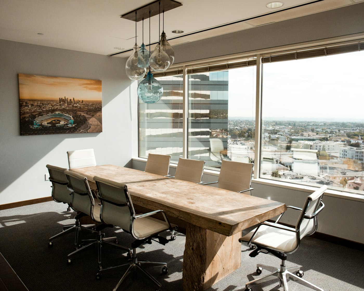 An elegant boardroom with a reclaimed wood table, designer chairs, and a city view